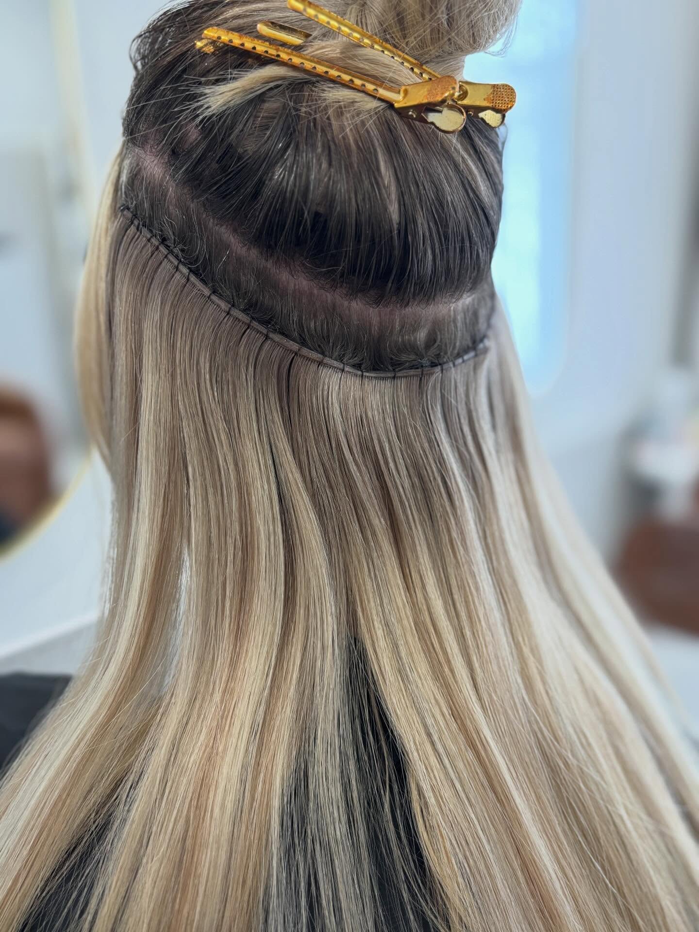 Hair extension weft being fitted, sectioned with clips